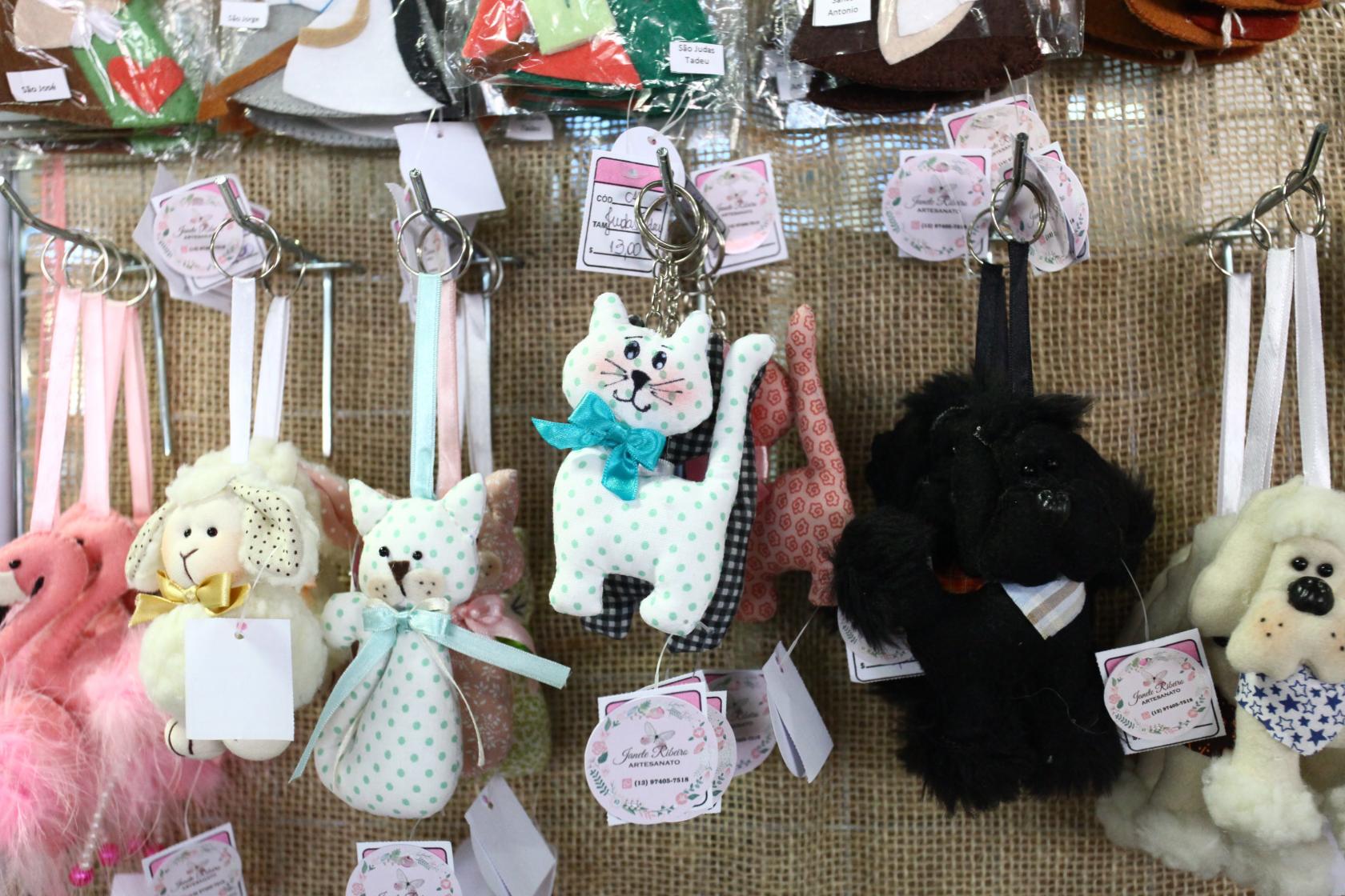 Gatos e outros animais de tecido pendurados para exposição. #Pracegover