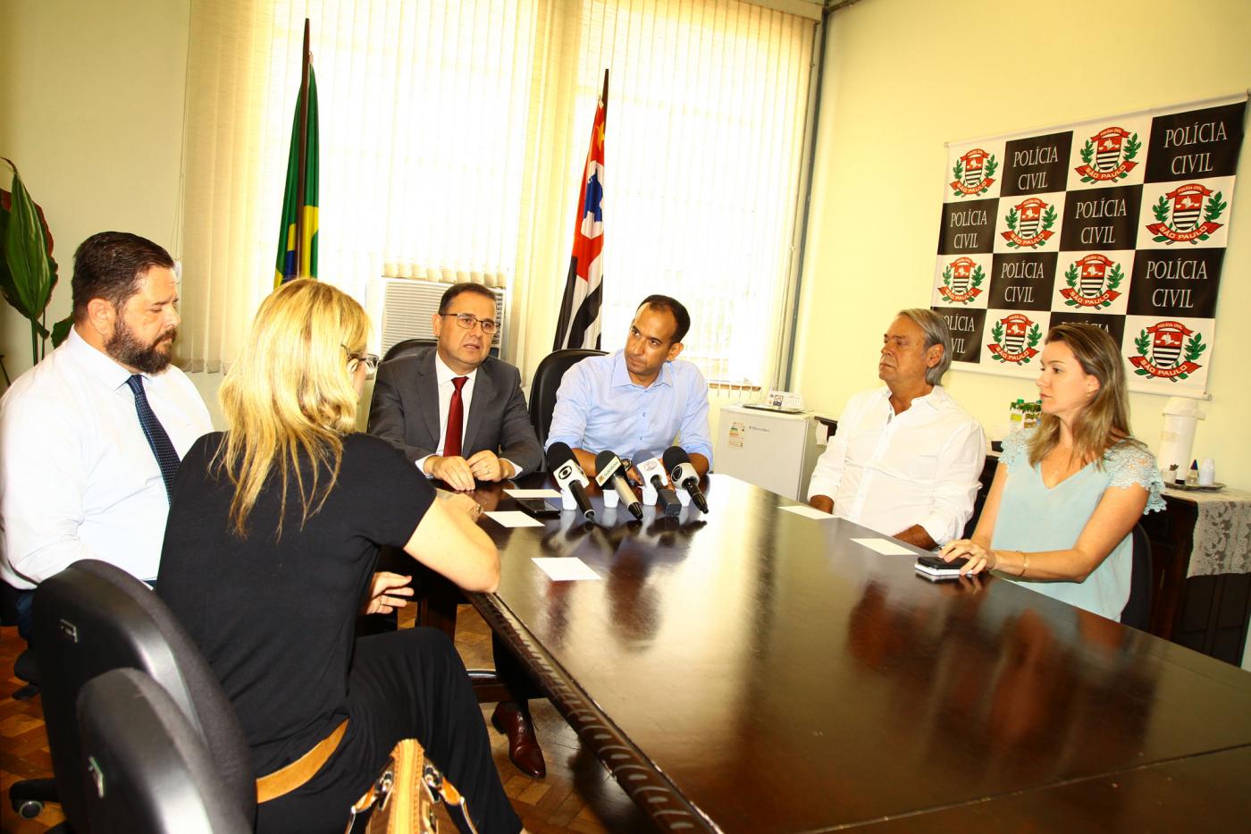 Em torno de uma mesa no PalÃ¡cio da PolÃ­cia estÃ£o diretor da PolÃ­cia Civil na Baixada Santista e Vale do Ribeira, Manoel Gatto Neto, o prefeito Paulo Alexandre Barbosa, outros delegados e secretÃ¡rios municipais, num total de seis pessoas. #Pracegover