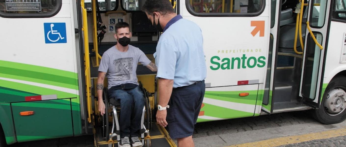 Profissionais passam por atualizações periódicas. Cadeirante sobre elevador de ônibus operado por motorista. #pratodosverem