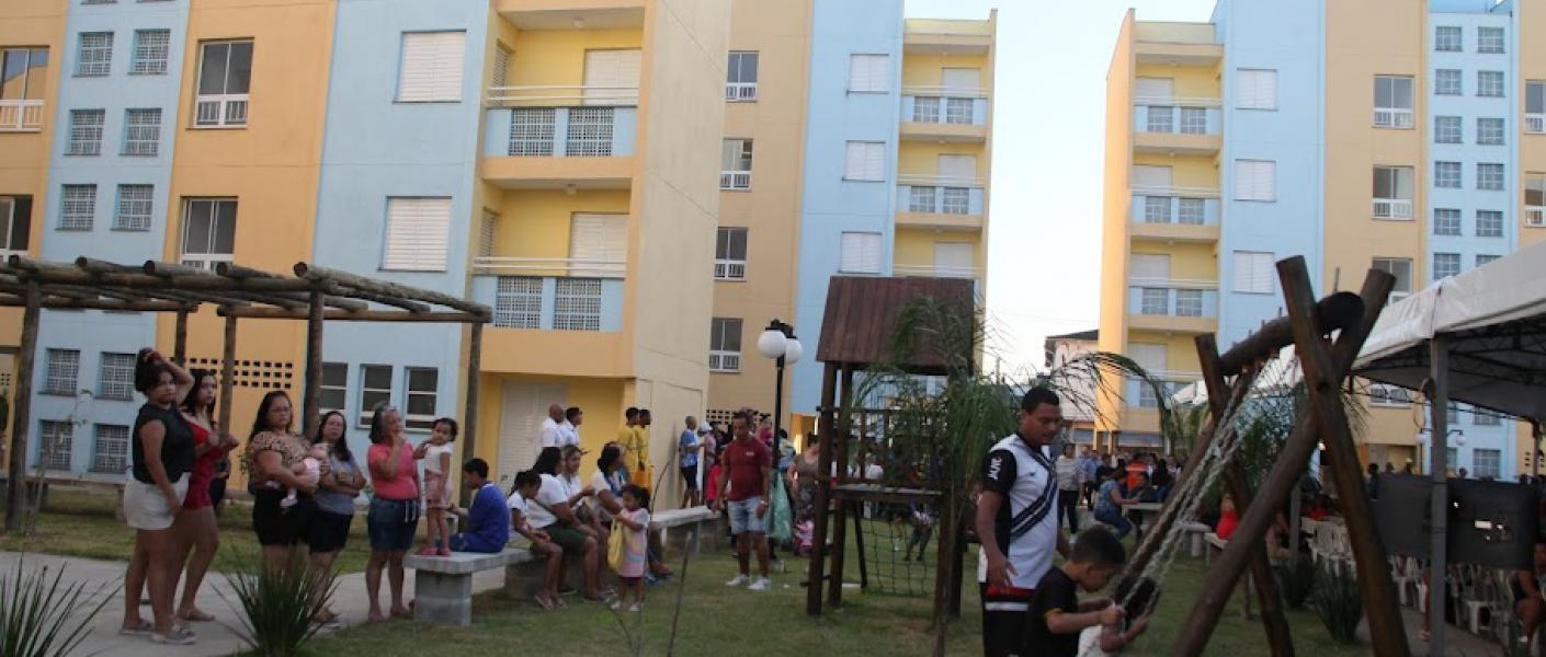 famílias na frente de conjunto habitacional #paratodosverem