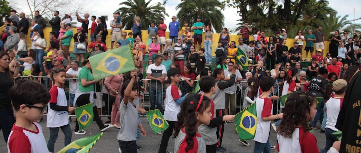 crianças desfilam pela avenida com bandeiras #paratodosverem 