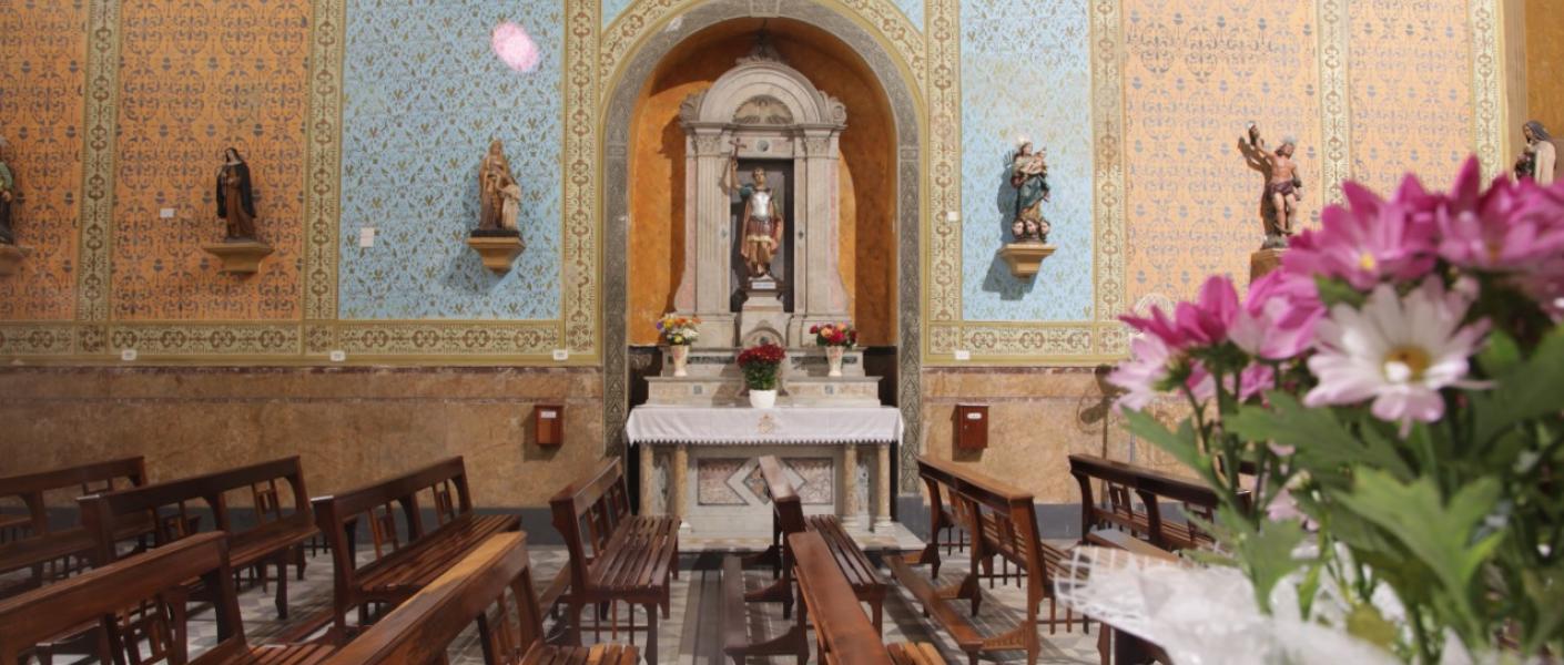 Interior da igreja do rosário, com bancos, paredes decoradas com azulejos e vitrais ao fundo. #paratodosverem