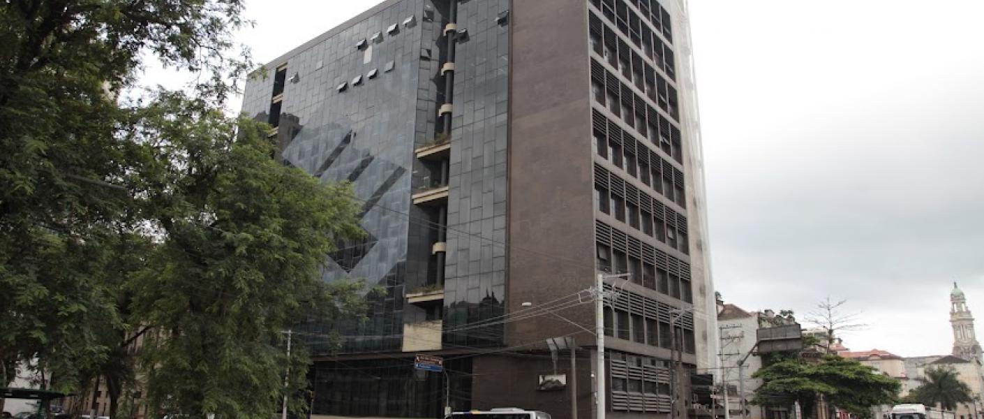 fachada do prédio onde está instalada a universidade, com grande avenida na frente. #paratodosverem