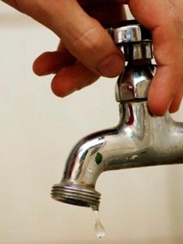 mão fecha torneira com gota pingando. #paratodosverem