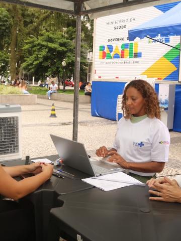 mulher sendo atendida em mesa na frente da carreta #paratodosverem