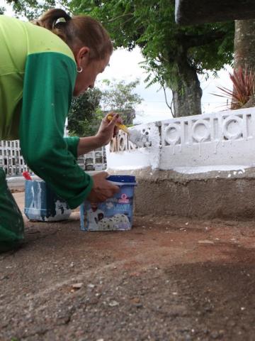 operária pintando guia em cemitério #paratodosverem