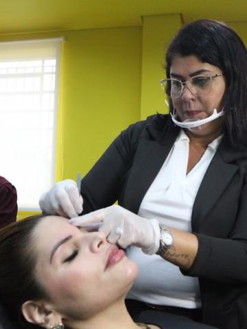 mulher faz a sobrancelha de outra sentada #paratodosverem