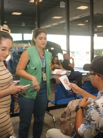 agente entrega panfleto a homem sentado #paratodosverem