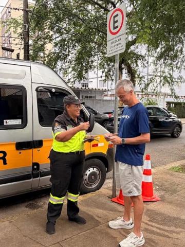 agente entrega panfleto a homem sentado #paratodosverem