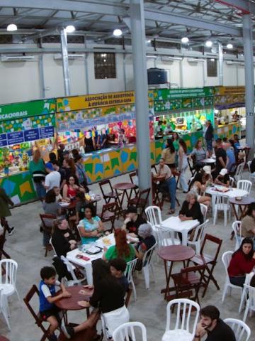 #paratodosverem galpão lotado com pessoas sentadas em cadeiras junto às mesas