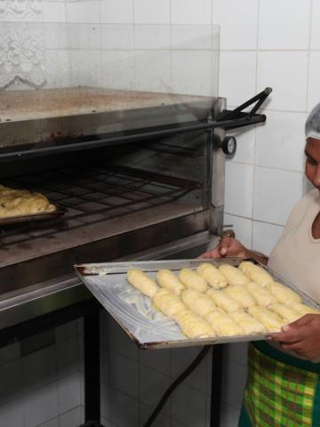 mulher olha pães retirados de forno #paratodosverem