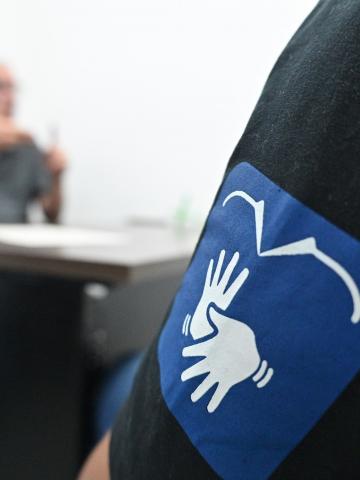 logo da central de libras em primeiro plano, com homem ao fundo. #paratodosverem