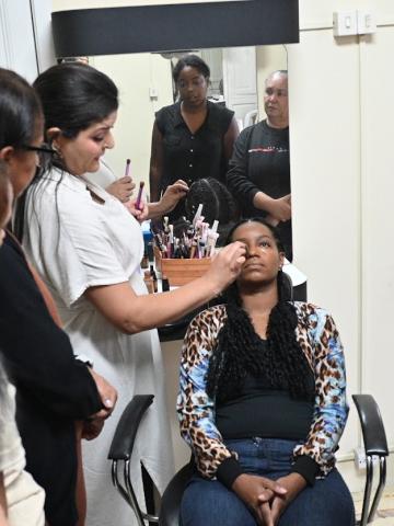alunas observam professora maquiando mulher #paratodosverem 