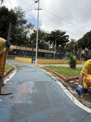 dois homens fazem manutenção em guia de área verde. #paratodosverem 