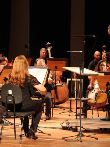 músicos de orquestra com maestro à frente. #paratodosverem 