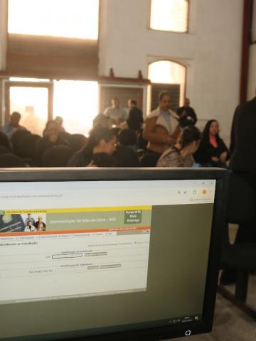 computador na frente de pessoas esperando atendimento #paratodosverem 