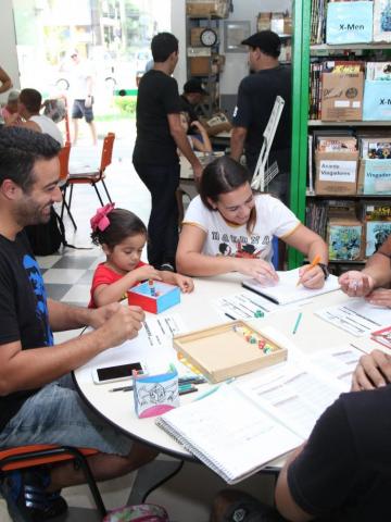 pessoas em mesa na gibiteca #paratodosverem