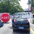 agente da CET na rua está abordando motorista que está dentro de carro. Ao fundo, um grande inflável onde se lê Pare. #paratodosverem