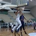 jogador está no ar fazendo cesta. Outro está ao lado tentando evitar a entrada da bola. #paratodosverem 