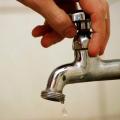 mão fecha torneira com gota pingando. #paratodosverem