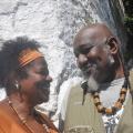 Casal de negros com bijuterias afro. Eles se olham. #Pracegover