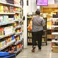 Mulher com sacola no corredor de um supermercado. #paratodosverem