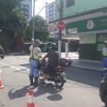 agente da CET aborda motociclista no meio da rua. à frente há um grande inflável onde se lê Pare. #paratodosverem