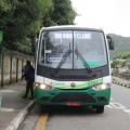 ônibus está parado em ponto em avenida, entre muro de edificação e um canal. #paratodosverem