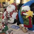 bonecos de papai noel e outros artigos de natal sobre uma mesa de exposição. #paratodosverem 