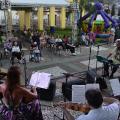 apresentação de conjunto de cordas e público ao fundo em um espaço aberto. #paratodosverem 