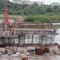 Grande estrutura de ferro rio adentro, com homens trabalhando. #Paratodosverem