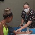 Mulher passa por aferição de pressão arterial com profissional de saúde, #paratodosverem