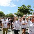 Grupo caminha pela avenida da orla debaixo de sol e vestido com camisas alusivas à prevenção do HIV. #pracegover