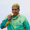 Ana Marcela 'morde' medalha de ouro vestida com uniforme da delegação do Brasil. #pracegover
