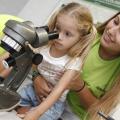 menina olha no microscópio ajudada por professora #pracegover 