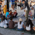 crianças na atividade olham para monitor sentadas em círculo #paratodosverem 
