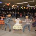 grupo com roupas típicas juninas dança quadrilha. #paratodosverem