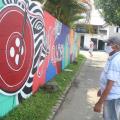grafite pintado em grande extensão de muro com homem olhando a pintura. #paratodosverem