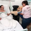 mulher pega cão no colo e o aproxima de paciente deitado #paratodosverem