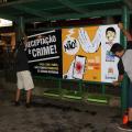 Dois jovens afixam cartaz em ponto de ônibus #paratodosverem