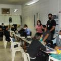 pessoas estão sentadas à mesa. De um lado, são atendentes. De outro, o público do centro de emprego. #paratodosverem 