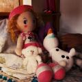 boneca e bichos de pelúcia sobre uma cama. #paratodosverem