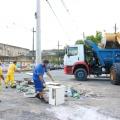 equipe de limpeza urbana está recolhendo entulho em calçada ao lado de trator e caminhão. #paratodosverem