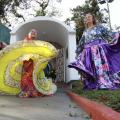mulheres vestidas com roupas típicas ciganas, dançam em frente a uma gruta. O movimento da dança roda as sais dos vestidos que se abrem. #paratodosverem