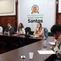 reunião com sete pessoas sentadas em torno de uma mesa. Ao fundo, um banner com o brasão da prefeitura. #paratodosverem