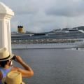 Homem de costa, com chapéu, observa a passagem de navio de cruzeiros pelo estuário de Santos. #paratodosverem