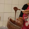 mão mexe em calda de chocolate dentro de vasilha. #paratodosverem