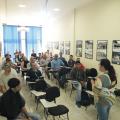 Alunos sentados observam orientadora falando de pé. #pracegover