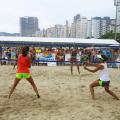 duas pessoas de costas , de frente para uma rede de esportes, em uma praia #paratodosverem