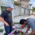 dois homens ajeitam floreira em rua. #paratodosverem